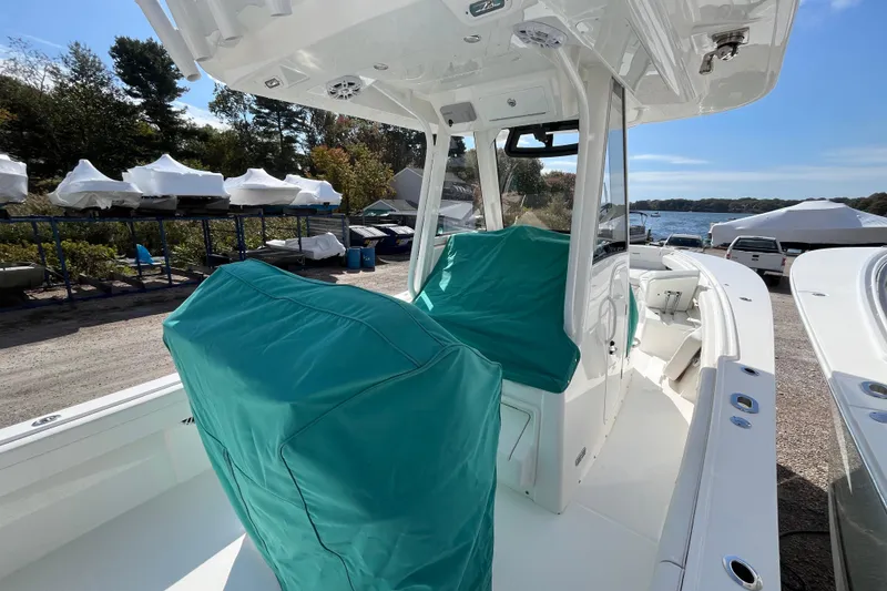 Slide: The Image of 2023 Regulator 28 boat with teal seat covers, docked near a scenic waterfront. - 54