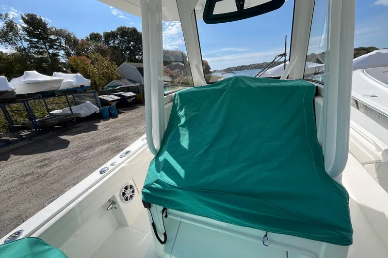 Slide: The Image of 2023 Regulator 28 boat interior with green cover, docked near trees and other boats. - 55