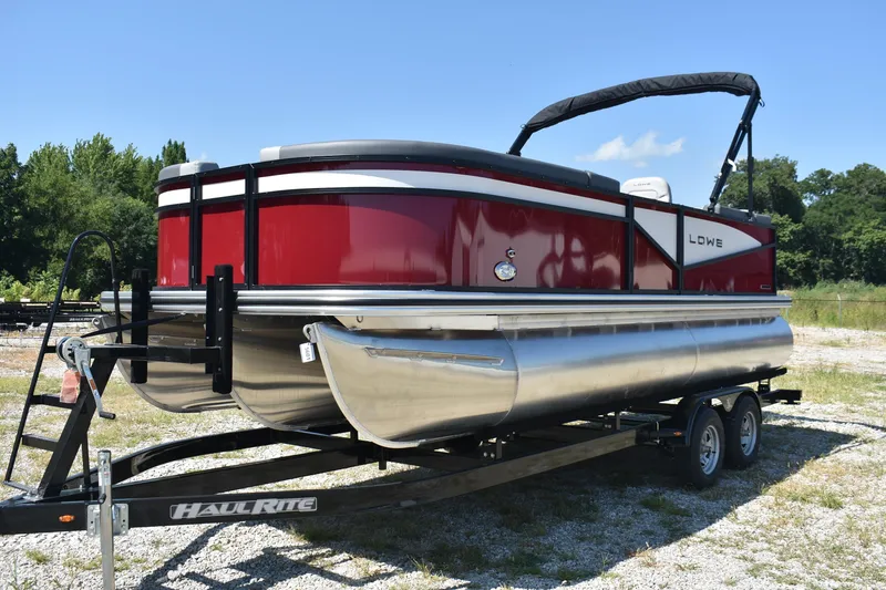 Slide: The Image of 2025 Lowe LS 210 WT pontoon boat on trailer, red and silver design, outdoors. - 1
