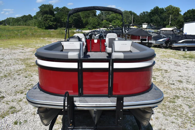 Slide: The Image of 2025 Lowe LS 210 WT pontoon boat, red exterior, parked on gravel lot with trees in background. - 2
