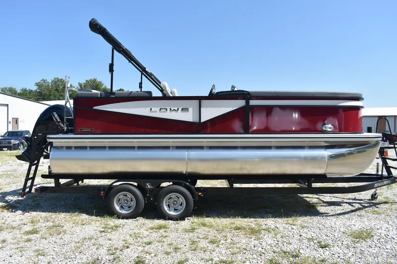 Slide: The Image of 2025 Lowe LS 210 WT pontoon boat on trailer, red and silver design, parked outdoors. - 4
