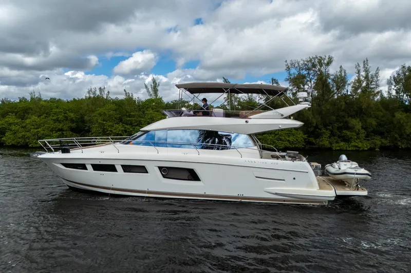 Slide: The Image of 2012 Prestige Flybridge yacht cruising on a river with lush greenery in the background. - 12