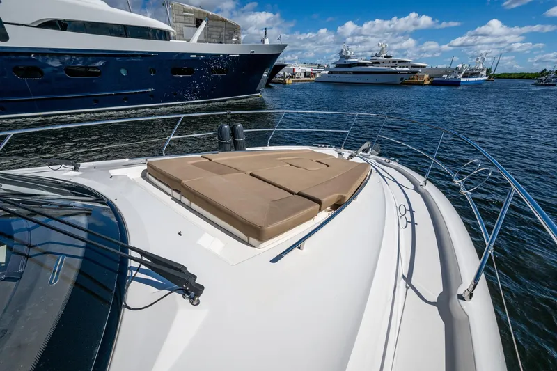 Slide: The Image of 2012 Prestige Flybridge yacht with sun pad, docked near luxury boats under blue sky. - 68