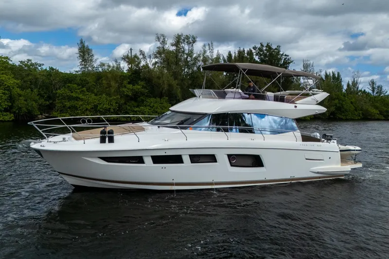 Slide: The Image of 2012 Prestige Flybridge yacht cruising on a scenic waterway with lush greenery. - 9