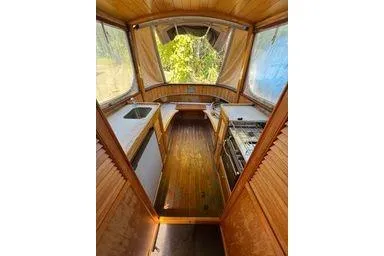 Slide: The Image of 2001 Logan 33 interior with wooden finish, featuring a compact kitchen and large windows. - 11