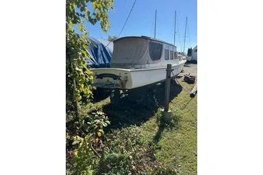 Slide: The Image of 2001 Logan 33 boat on grass, partially covered, with clear blue sky. - 7