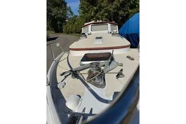 Slide: The Image of 2001 Logan 33 boat deck with winch, surrounded by trees and blue tarp. - 8