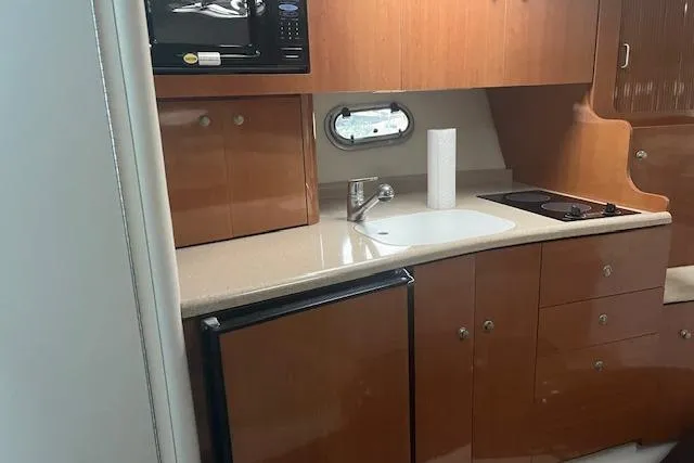 Slide: The Image of 2000 Four Winns 328 Vista boat kitchen with wood cabinets, sink, stove, and microwave. - 13