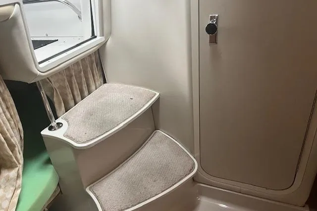 Slide: The Image of Interior stairs of 2000 Four Winns 328 Vista boat, featuring carpeted steps and a cabin door. - 16