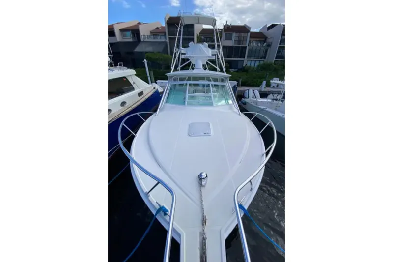 Slide: The Image of 1996 Cabo 31 Express boat docked, front view with clear sky background. - 2
