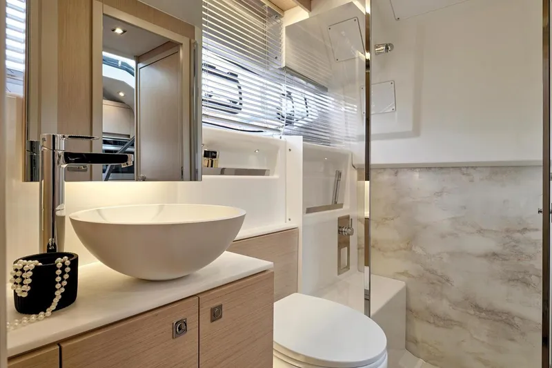 Slide: The Image of 2024 Jeanneau DB43 yacht with triple Mercury outboards, cruising in a scenic waterfront setting. - 12