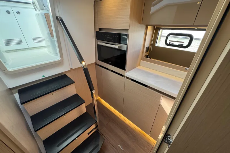 Slide: The Image of 2024 Jeanneau DB43 interior with modern kitchen, sleek cabinetry, and staircase. - 33