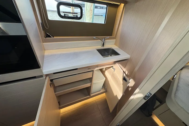 Slide: The Image of 2024 Jeanneau DB43 yacht interior kitchen with sink, cabinets, and window view. - 35