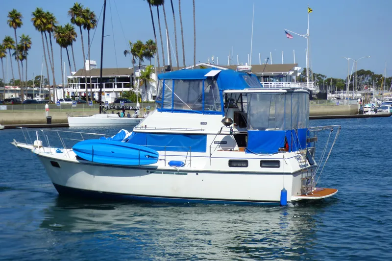 Slide: The Image of 1985 Carver 3607 Aft Cabin Motor Yacht with blue canopy, docked in a marina. - 3