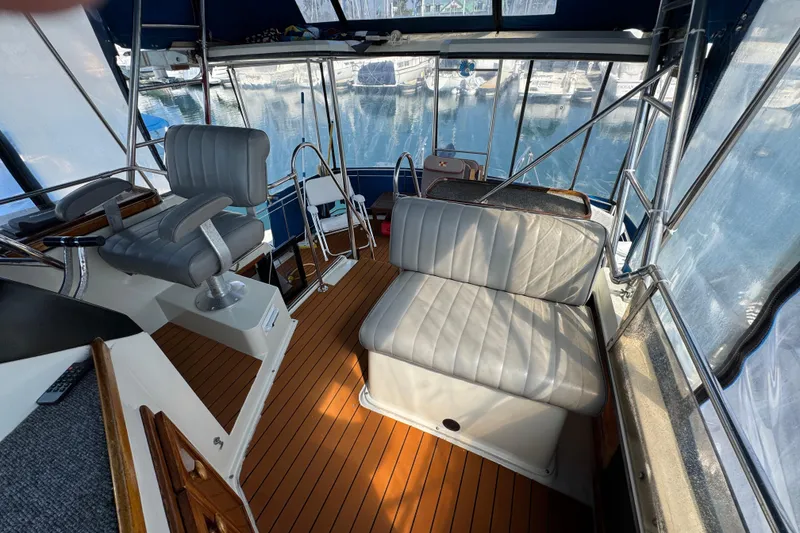 Slide: The Image of 1985 Carver 3607 Aft Cabin Motor Yacht interior with seating and helm, docked at marina. - 31