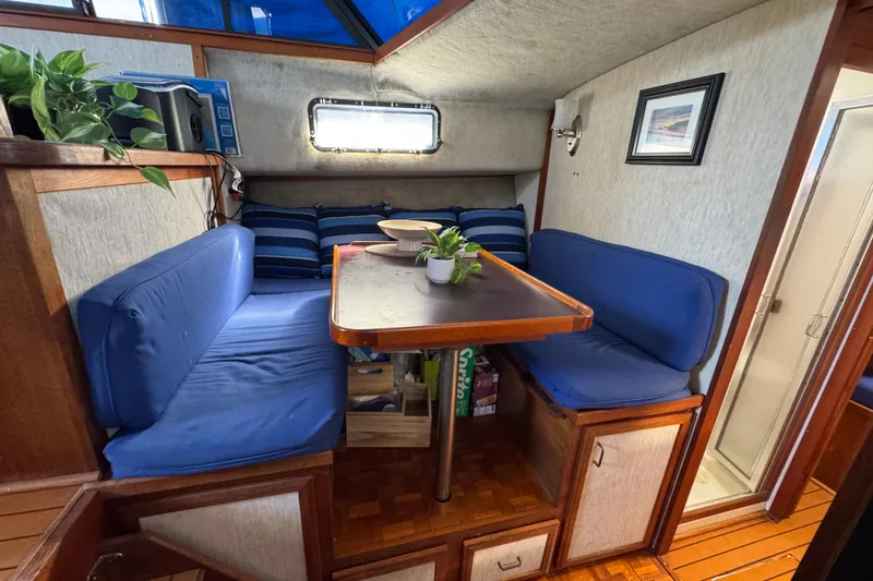 Slide: The Image of 1985 Carver 3607 Aft Cabin Motor Yacht interior with cozy dining area and blue cushions. - 52