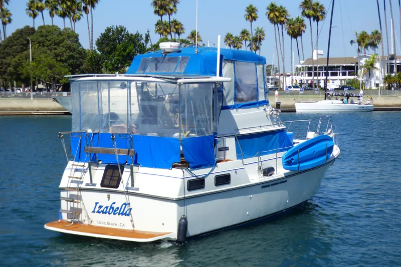Slide: The Image of 1985 Carver 3607 Aft Cabin Motor Yacht in marina, blue canopy, palm trees in background. - 6