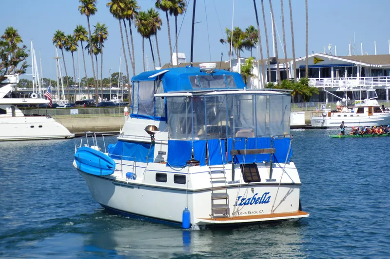 Slide: The Image of 1985 Carver 3607 Aft Cabin Motor Yacht in marina, blue canopy, palm trees in background. - 7