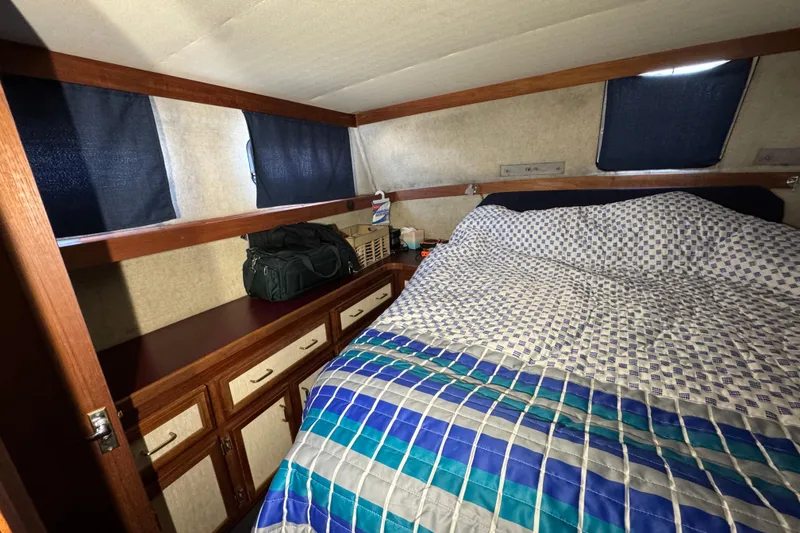 Slide: The Image of 1985 Carver 3607 Aft Cabin Motor Yacht bedroom with patterned bedding and storage cabinets. - 71