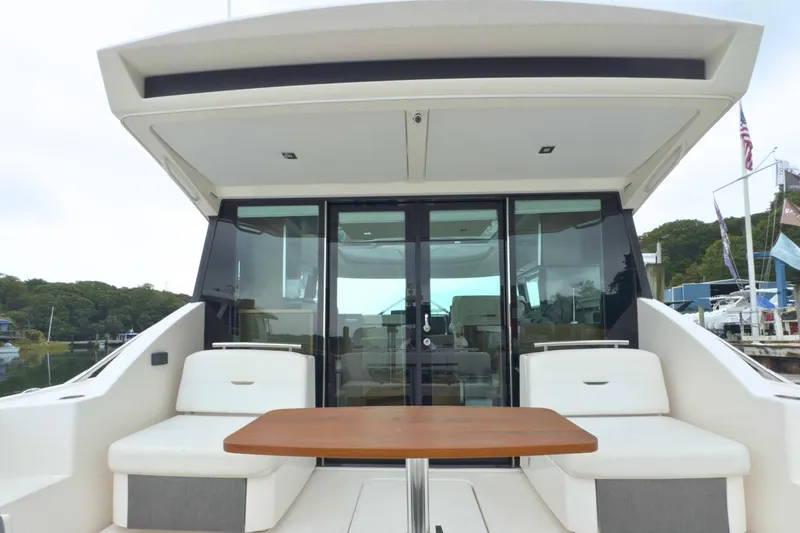 Slide: The Image of 2018 Tiara Yachts C44 Coupe with outdoor seating and table, docked at marina. - 19
