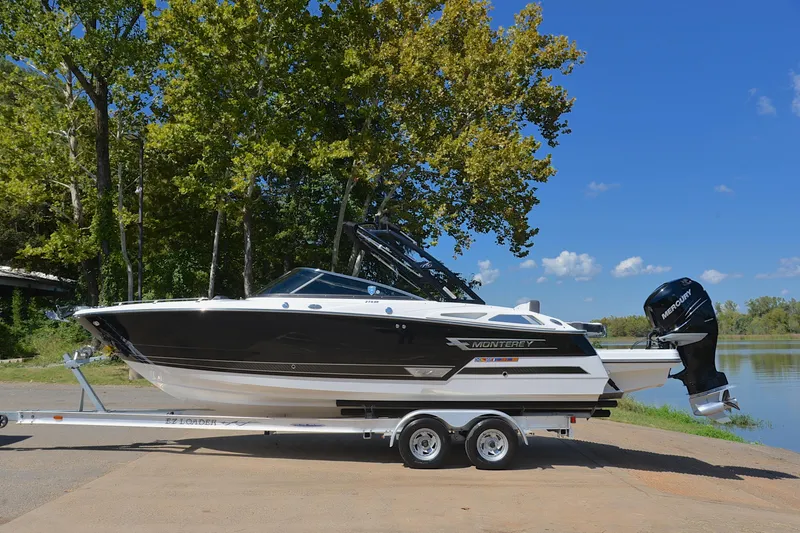 Slide: The Image of 2023 Monterey 275SS Super Sport boat on trailer by a lake, under clear blue sky. - 12