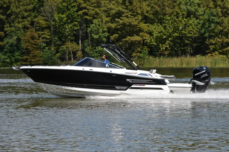 Slide: The Image of 2023 Monterey 275SS Super Sport boat cruising on a lake with lush green trees. - 2