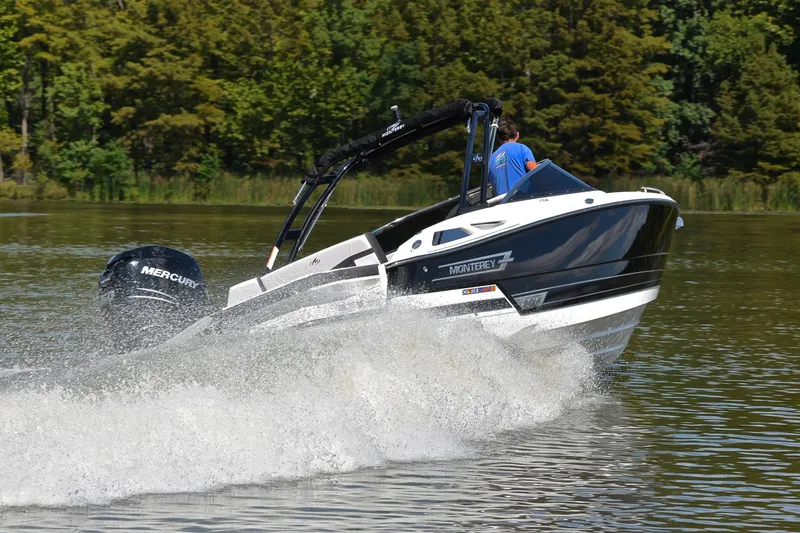 Slide: The Image of 2023 Monterey 275SS Super Sport boat cruising on a lake with lush green trees. - 5