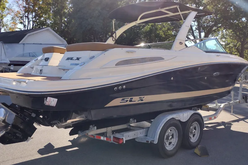 Slide: The Image of 2014 Sea Ray 270 SLX boat on trailer, parked outdoors in sunny setting. - 6