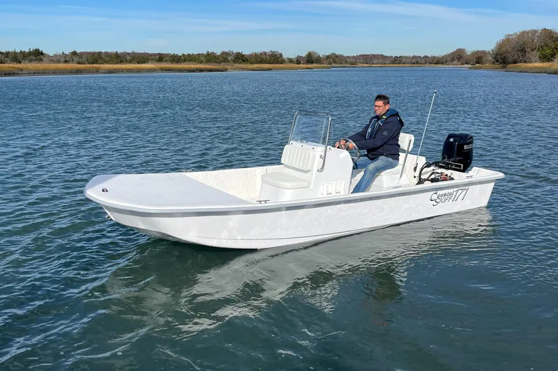 The Image of 2025 Coastal Skiff 171 boat on calm water with a person steering. - 0