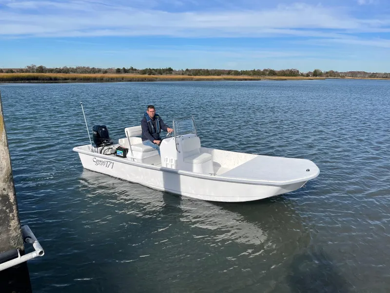 Slide: The Image of 2025 Coastal Skiff 171 boat on calm water with a person onboard. - 3