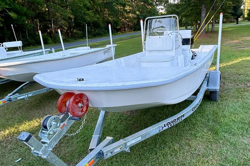 Slide: The Image of 2025 Coastal Skiff 171 boat on trailer, parked on grass, ready for adventure. - 8