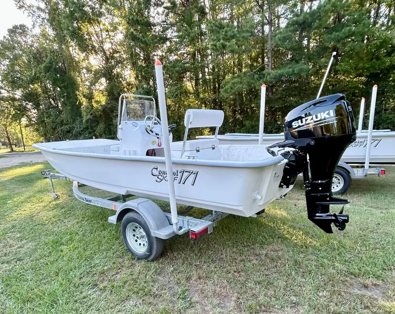 Slide: The Image of 2025 Coastal Skiff 171 boat with Suzuki motor on a trailer, parked on grass. - 9