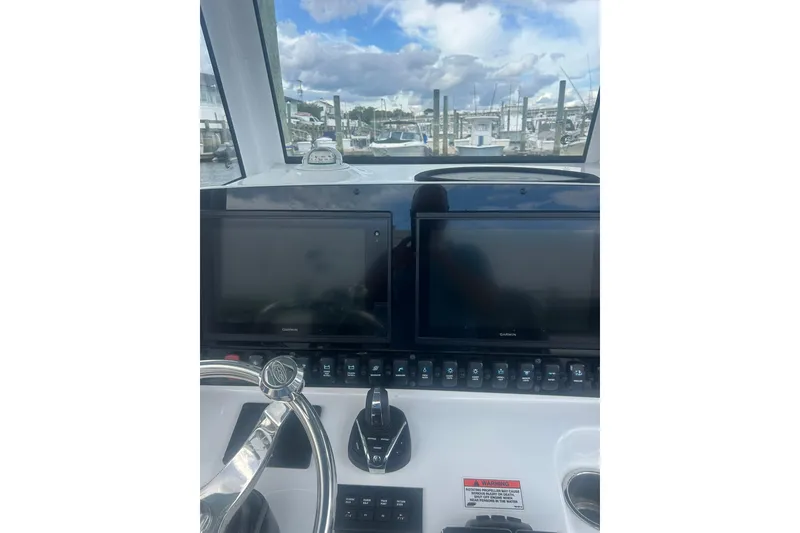 Slide: The Image of 2021 Sea Hunt Gamefish 27 Coffin Box helm with dual Garmin displays and marina view. - 7