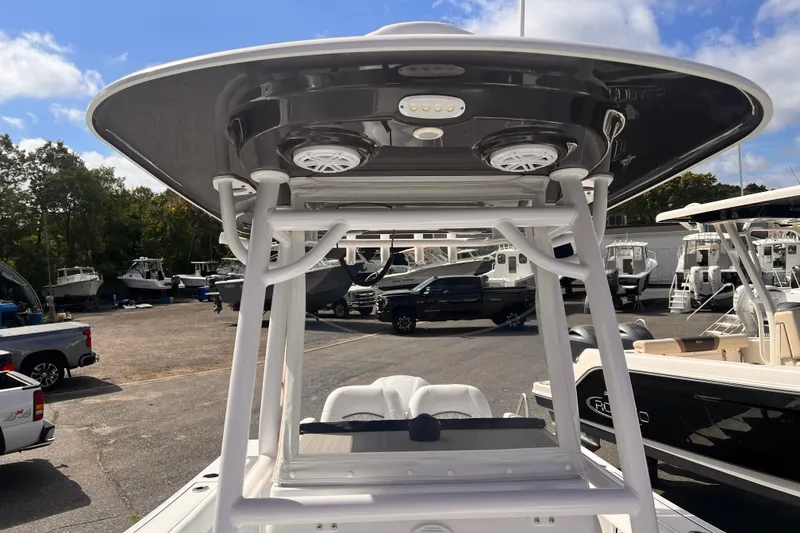 Slide: The Image of 2024 Sportsman Open 242 Center Console boat with T-top and speakers, in a marina setting. - 8
