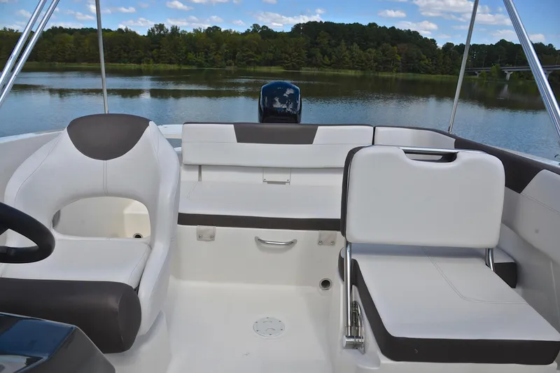 Slide: The Image of 2018 Bayliner VR5 Bowrider OB interior with white seating, on a serene lake backdrop. - 22