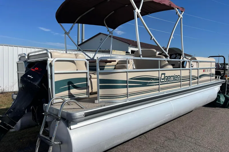 Slide: The Image of 2002 Premier 225 Majestic pontoon boat with canopy and outboard motor, parked outdoors. - 2