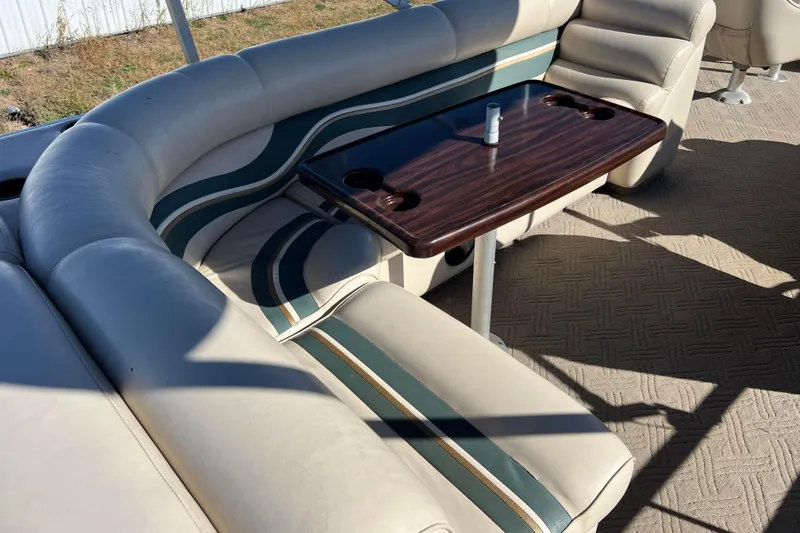 Slide: The Image of Premier 225 Majestic 2002 boat interior with cushioned seating and wooden table. - 26