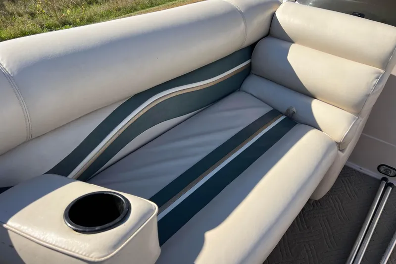 Slide: The Image of 2002 Premier 225 Majestic boat seat with cup holder, featuring white and teal upholstery. - 28