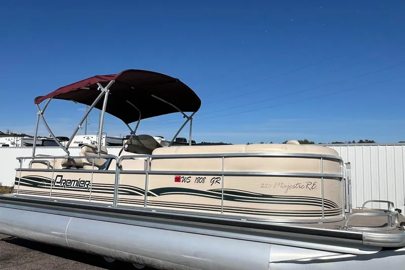 Slide: The Image of 2002 Premier 225 Majestic pontoon boat with canopy, parked outdoors under clear blue sky. - 44