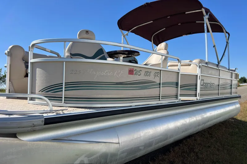 Slide: The Image of 2002 Premier 225 Majestic pontoon boat with canopy, docked on grassy shore. - 7