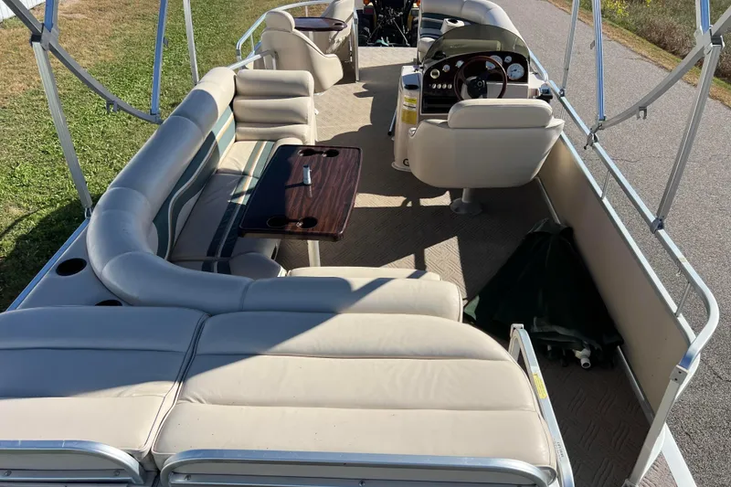 Slide: The Image of 2002 Premier 225 Majestic pontoon boat interior with beige seating and steering console. - 9