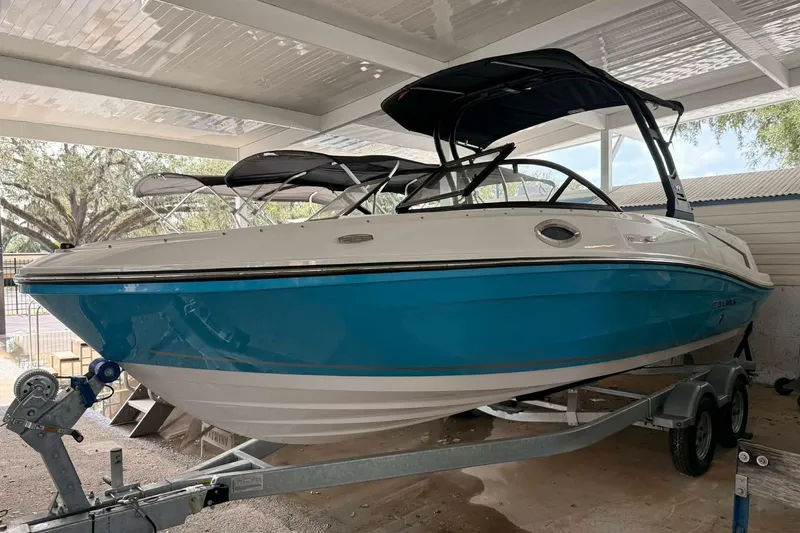 The Image of 2026 Bayliner VR6 Bowrider OB boat with blue hull on trailer under shelter. - 0