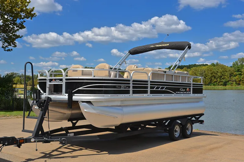 Slide: The Image of 2023 Sun Tracker Fishin' Barge 20 DLX pontoon boat on trailer by a lake. - 10