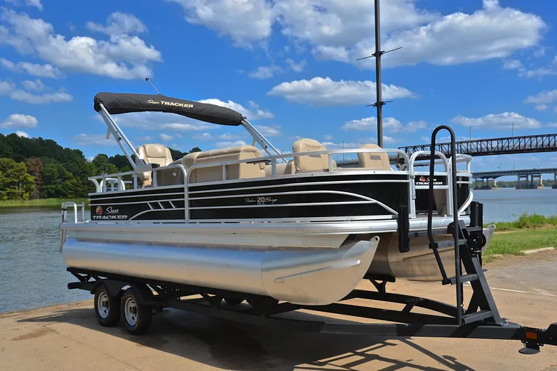 Slide: The Image of 2023 Sun Tracker Fishin' Barge 20 DLX pontoon boat on trailer by a scenic lake. - 16