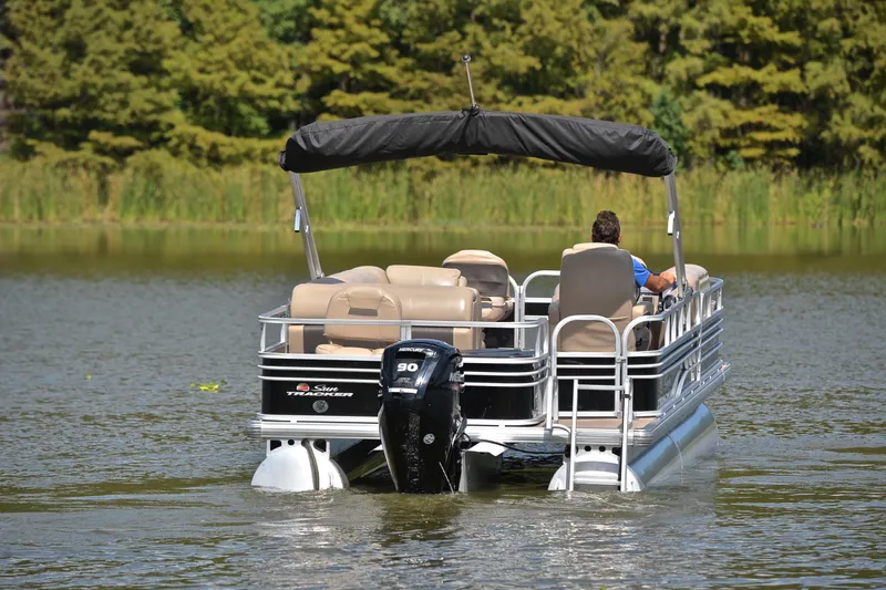 Slide: The Image of 2023 Sun Tracker Fishin' Barge 20 DLX pontoon boat cruising on a serene lake. - 7