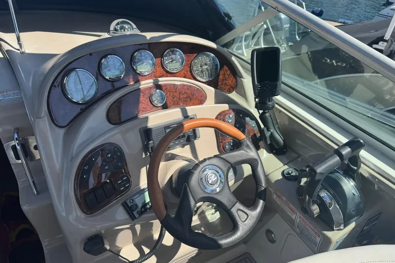 Slide: The Image of 2005 Sea Ray 280 Sundancer helm with gauges, steering wheel, and controls. - 14