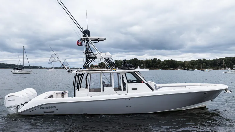 Slide: The Image of 2017 Everglades 435 CC boat on water, cloudy sky, other boats in background. - 2
