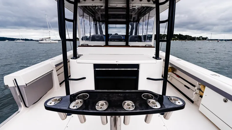 Slide: The Image of 2017 Everglades 435 CC boat interior with rod holders, on a calm water backdrop. - 22