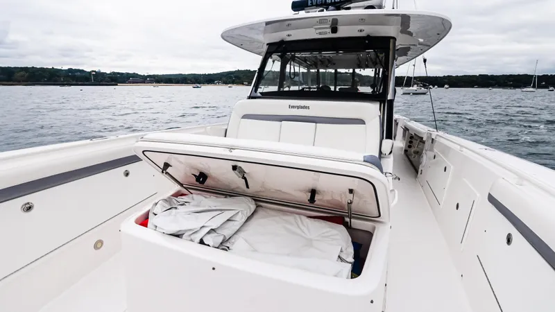 Slide: The Image of 2017 Everglades 435 CC boat with open storage compartment on deck, docked on calm water. - 46