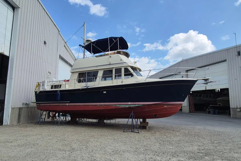 Slide: The Image of 1990 Sabreline 36 Fast Trawler docked outside a warehouse under a blue sky. - 2